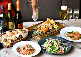 前菜、サラダ、パスタ、チキン、パン、お酒が並んでいる