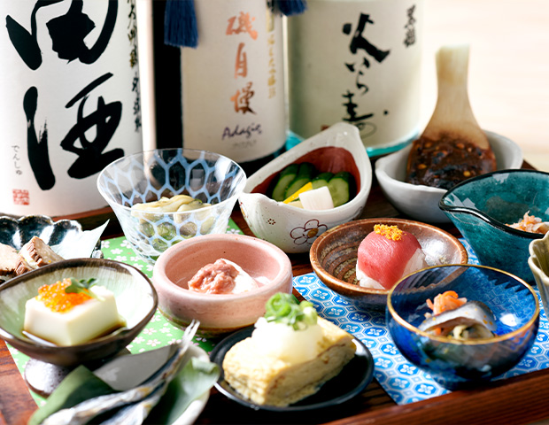 12種類の本日のアテに、田酒や磯自慢など日本酒の一升瓶が並んでいる